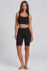Woman wearing a black sports bra and shorts on a white background