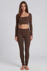 Woman wearing a brown long-sleeve crop top and leggings on a white background